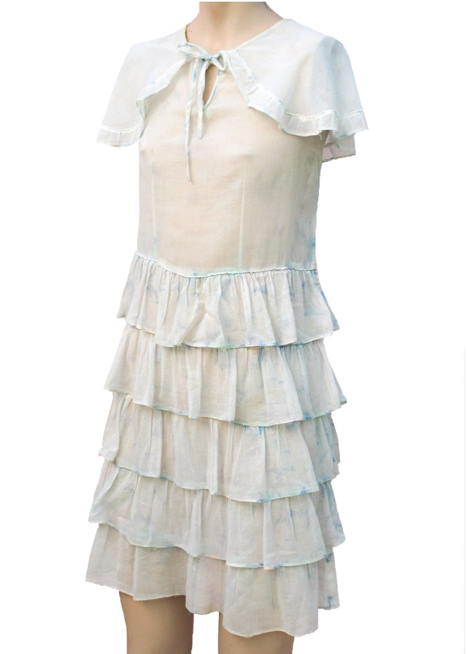 antique 1920s white cotton ruffle dress for a young girl or teen. Sleeveless with layers of ruffle frill and attached capelet.