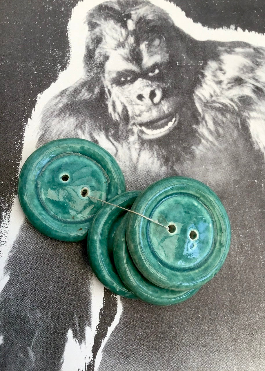 a set of four huge green glazed ceramic vintage buttons, with a picture of king kong behind