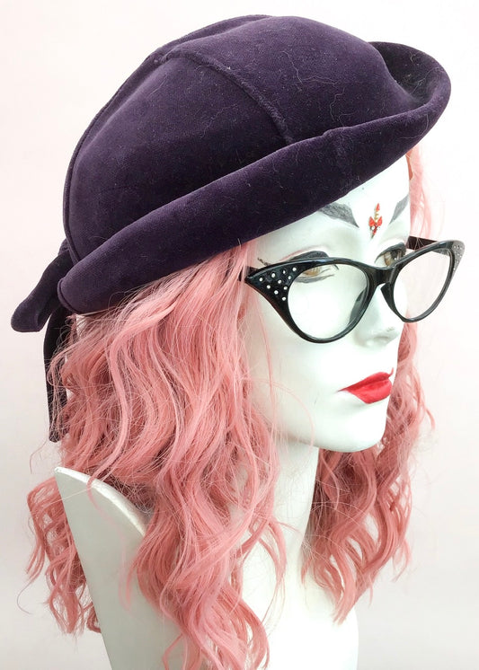 Vintage plum velvet tilt hat, with a bow at the back, made by eastex with original tag